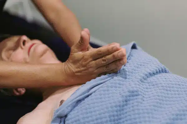 Close-up of a therapist's hand massaging a patient's shoulder during a treatment session