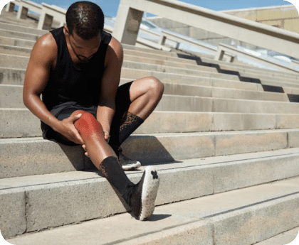 Man sitting on outdoor steps holding his knee in pain