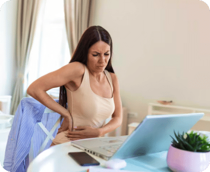 Woman sitting at a laptop holding her abdomen in pain
