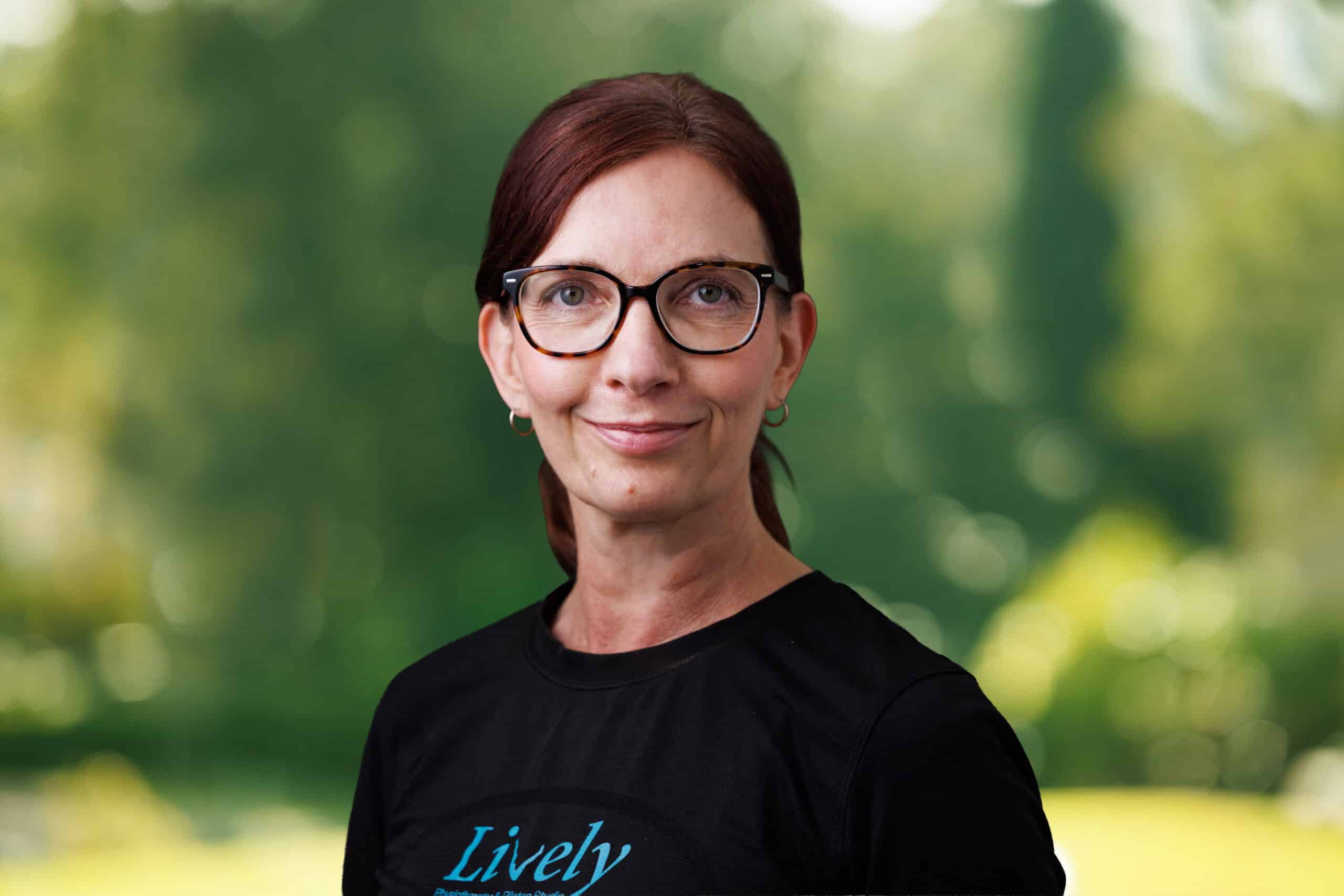 Debbie Virdi, team member at Lively Physio, smiling outdoors in a black Lively Physio top
