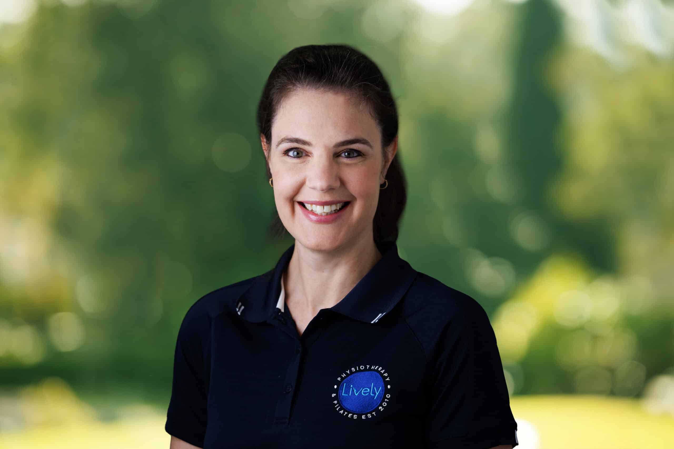 Sally Edwards, team member at Lively Physio, smiling outdoors in a navy Lively Physio polo shirt